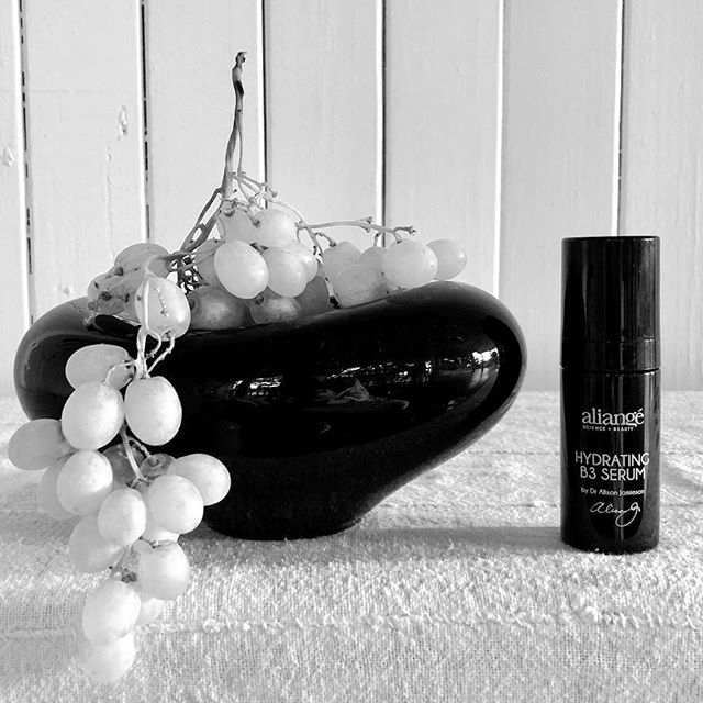 Aliangé Hydrating B3 Serum styled in black and white with grapes and a ceramic dish — niacinamide article