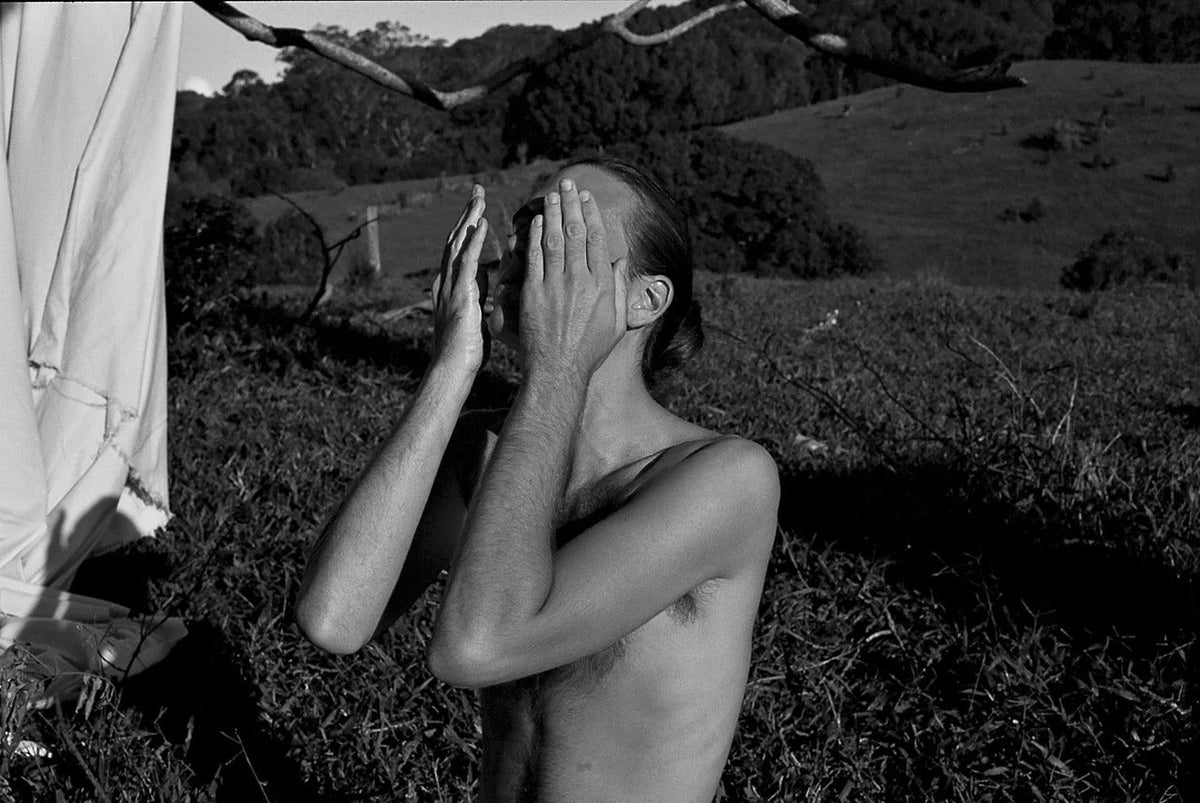 Woman in black and white kneeling on grass with her hands over her face — AHAs versus BHAs article