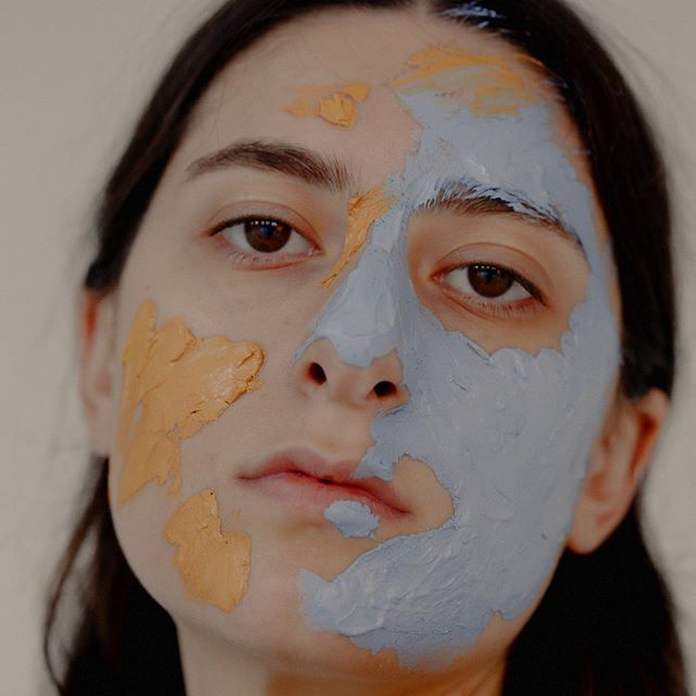 Young woman with patches of yellow and blue masque applied across her face — teen acne article