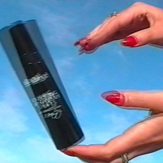 Aliangé black bottle held between two hands against a blue sky — careers in aesthetics article